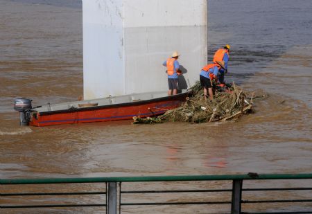 Some street cleaners collect garbage under a bridge along the Liujiang River after the flood receded in Liuzhou City of southwest China's Guangxi Zhuang Autonomous Region, on July 7, 2009. The flood passing through Liujiang River receded on July 6 and local people began to clean the city and restore the basic facilities.