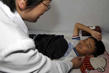 A doctor carries out the psychological intervention treatment for a boy who was injured in the deadly July 5 riot at a hospital in Urumqi, capital of northwest China's Xinjiang Uygur Autonomous Region, on July 7, 2009.