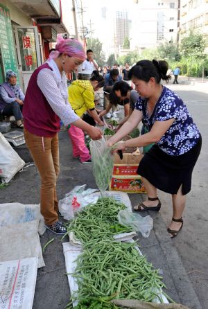 People buy vegetables in Urumqi, capital of northwest China's Xinjiang Uygur Autonomous Region, on July 8, 2009. 