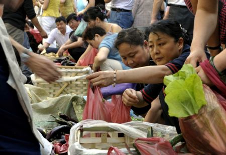 People buy vegetables at a market in Urumqi, capital of northwest China's Xinjiang Uygur Autonomous Region, on July 8, 2009.