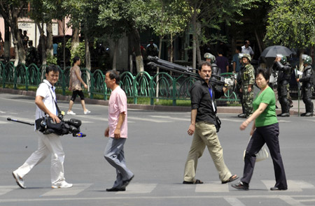 Overseas journalists carrying equipment walk on a street in Urumqi, capital of northwest China's Xinjiang Uygur Autonomous Region, on July 8, 2009.