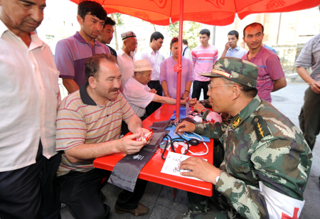 Residents consult a medical member of the Armed Police during a community free medical service at a street in Urumqi, capital of northwest China's Xinjiang Uygur Autonomous Region on July 9, 2009.