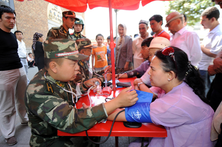 Residents consult a medical member of the Armed Police during a community free medical service at a street in Urumqi, capital of northwest China's Xinjiang Uygur Autonomous Region July 9, 2009.