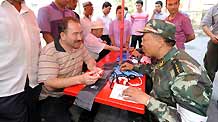 Residents consult a medical member of the Armed Police during a community free medical service at a street in Urumqi, capital of northwest China's Xinjiang Uygur Autonomous Region on July 9, 2009.