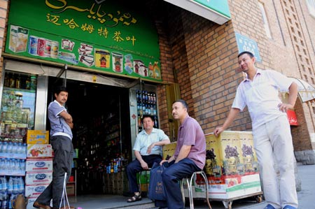 People rest at a shop in business in the Erdaoqiao area in Urumqi, capital of northwest China's Xinjiang Uygur Autonomous Region, on July 9, 2009. Shopping malls, supermarkets, agricultural product markets and gas stations are resuming business in the riot-torn Urumqi.