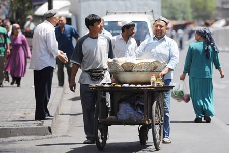 A vendor sells food in the Erdaoqiao area in Urumqi, capital of northwest China's Xinjiang Uygur Autonomous Region, on July 9, 2009. Shopping malls, supermarkets, agricultural product markets and gas stations are resuming business in the riot-torn Urumqi. 