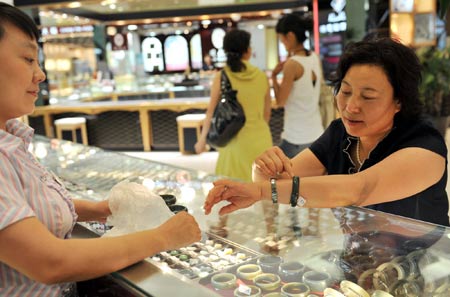 A customer (R) selects jewelry at the Wangfujing shopping mall in Urumqi, capital of northwest China's Xinjiang Uygur Autonomous Region, on July 9, 2009. Shopping malls, supermarkets, agricultural product markets and gas stations are resuming business in the riot-torn Urumqi.