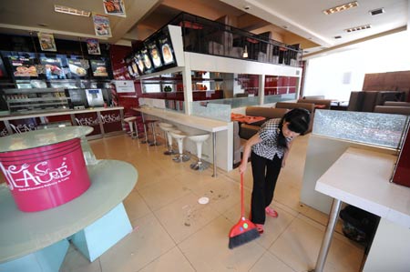 An employee cleans a restaurant in the Erdaoqiao area in Urumqi, capital of northwest China's Xinjiang Uygur Autonomous Region, on July 9, 2009. Shopping malls, supermarkets, agricultural product markets and gas stations are resuming business in the riot-torn Urumqi.