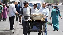 A vendor sells food in the Erdaoqiao area in Urumqi, capital of northwest China's Xinjiang Uygur Autonomous Region, on July 9, 2009. Shopping malls, supermarkets, agricultural product markets and gas stations are resuming business in the riot-torn Urumqi.