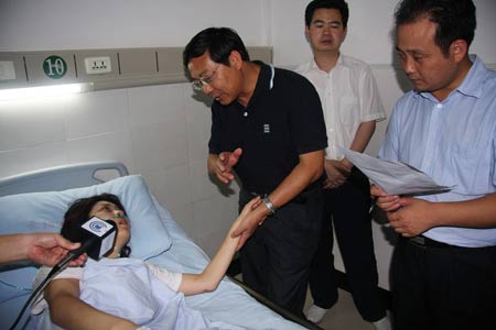Local officials visit an injured tourist at the People's Hospital in Yunyang County, southwest China's Chongqing municipality on July 11, 2009.