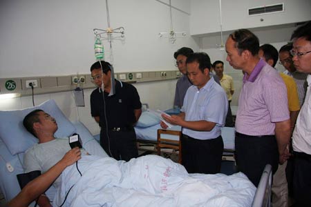 Local officials visit an injured tourist at the People's Hospital in Yunyang County, southwest China's Chongqing municipality on July 11, 2009.