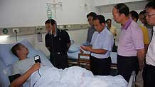 Local officials visit an injured tourist at the People's Hospital in Yunyang County, southwest China's Chongqing municipality on July 11, 2009.