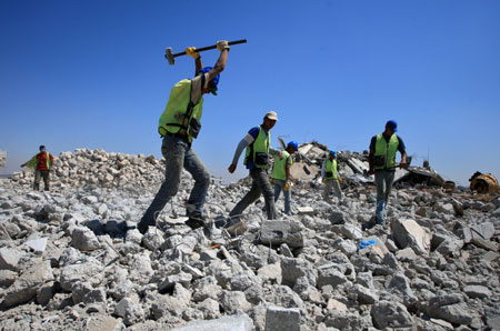 Palestinian workers of the United Nations Relief and Works Agency (UNRWA) clear the rubble of houses that were destroyed during Israel's war on Gaza in Izbet Abed Rabbo in Jabalia refugee camp, northern Gaza Strip, on July 11, 2009. Removing the rubble is the first step taken on the ground by the UN as part of the reconstruction plan for Gaza after the war. 