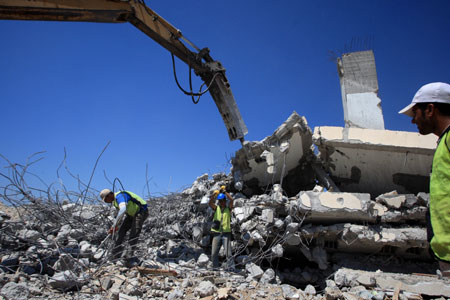 Palestinian workers of the United Nations Relief and Works Agency (UNRWA) clear the rubble of houses that were destroyed during Israel's war on Gaza in Izbet Abed Rabbo in Jabalia refugee camp, northern Gaza Strip, on July 11, 2009. Removing the rubble is the first step taken on the ground by the UN as part of the reconstruction plan for Gaza after the war.