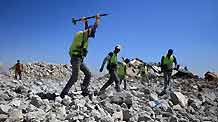 Palestinian workers of the United Nations Relief and Works Agency (UNRWA) clear the rubble of houses that were destroyed during Israel's war on Gaza in Izbet Abed Rabbo in Jabalia refugee camp, northern Gaza Strip, on July 11, 2009. Removing the rubble is the first step taken on the ground by the UN as part of the reconstruction plan for Gaza after the war.