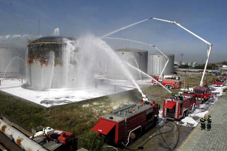Firefighters spray water to a blasted oil tank in Urumqi, capital of northwest China's Xinjiang Uygur Autonomous Region, on July 12, 2009.