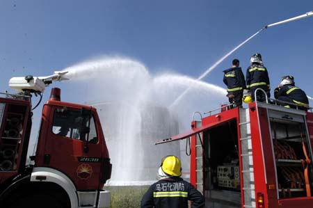 Firefighters spray water to a blasted oil tank in Urumqi, capital of northwest China's Xinjiang Uygur Autonomous Region, on July 12, 2009.
