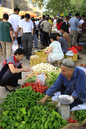 A vendor (R) sells vegetables at a market in Kashgar city, northwest China's Xinjiang Uygur Autonomous Region, on July 12, 2009. Businesses have recovered and prices have fallen to normal level in the city. 