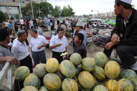 Citizens choose melons at a market in Kashgar city, northwest China's Xinjiang Uygur Autonomous Region, on July 12, 2009. Businesses have recovered and prices have fallen to normal level in the city. 