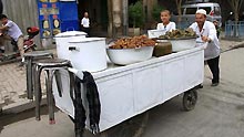 A vendor pulls a food cart in Kashgar city, northwest China's Xinjiang Uygur Autonomous Region, on July 12, 2009. Businesses have recovered and prices have fallen to normal level in the city.