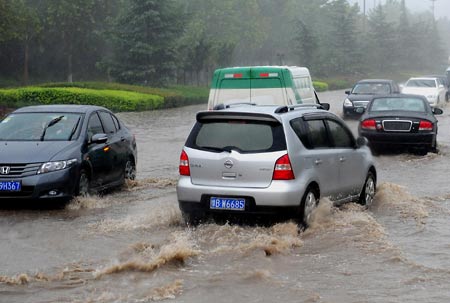 Vehicles run at a flooded street in Zhengzhou, capital of central China's Henan Province, on July 13, 2009. A heavy rain hit the city early Monday and a blue alarm had been announced. 