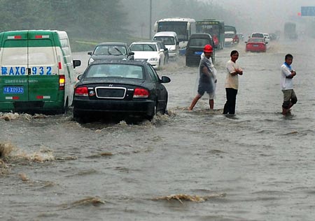 Vehicles run at a flooded street in Zhengzhou, capital of central China's Henan Province, on July 13, 2009. A heavy rain hit the city early Monday and a blue alarm had been announced. 