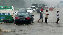 Vehicles run at a flooded street in Zhengzhou, capital of central China's Henan Province, on July 13, 2009. A heavy rain hit the city early Monday and a blue alarm had been announced.