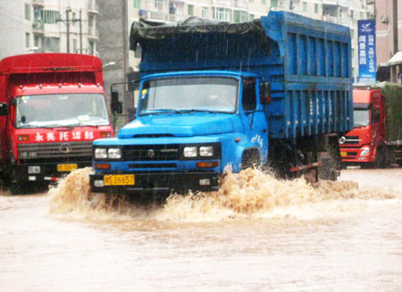 Vehicles wade through the inundated street at the Nanba Town of Yihan County in Dazhou City, southwest China&apos;s Sichuan Province, on July 11, 2009. 