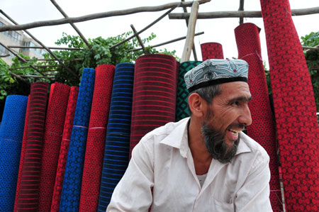 A vendor sells carpets at the largest bazaar in Aksu, northwest China's Xinjiang Uygur Autonomous Region, on July 12, 2009. Local residents of various ethnic groups went to bazaars, their traditional markets, for shopping on Sunday. 