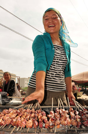 A woman sells kebab at the largest bazaar in Aksu, northwest China's Xinjiang Uygur Autonomous Region, on July 12, 2009. Local residents of various ethnic groups went to bazaars, their traditional markets, for shopping on Sunday.