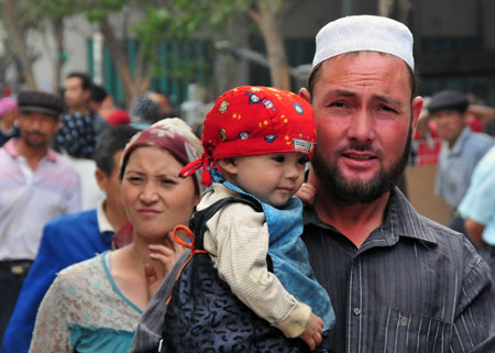 A man with a child in arm enjoys shopping at the largest bazaar in Aksu, northwest China's Xinjiang Uygur Autonomous Region, on July 12, 2009. Local residents of various ethnic groups went to bazaars, their traditional markets, for shopping on Sunday. 