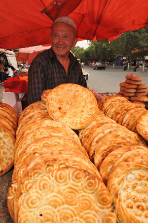 A vendor sells naan at a bazaar in Yining, northwest China's Xinjiang Uygur Autonomous Region, on July 12, 2009. Local residents of various ethnic groups went to bazaars, their traditional markets, for shopping on Sunday.