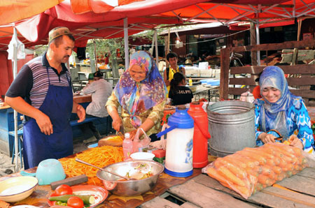 Vendors make food at a bazaar in Yining, northwest China's Xinjiang Uygur Autonomous Region, on July 12, 2009. Local residents of various ethnic groups went to bazaars, their traditional markets, for shopping on Sunday. 