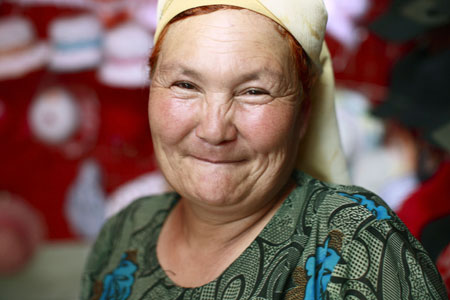 A vendor smiles at a bazaar in Yining, northwest China's Xinjiang Uygur Autonomous Region, July 12, 2009. Local residents of various ethnic groups went to bazaars, their traditional markets, for shopping on Sunday. (Xinhua/Cai Yang)