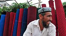 A vendor sells carpets at the largest bazaar in Aksu, northwest China's Xinjiang Uygur Autonomous Region, on July 12, 2009. Local residents of various ethnic groups went to bazaars, their traditional markets, for shopping on Sunday.