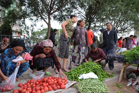 Citizens choose vegetables at a market in Kashgar city, northwest China's Xinjiang Uygur Autonomous Region, on July 12, 2009. Businesses have recovered and prices have fallen to normal level in the city.