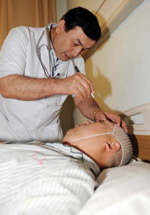 A doctor of Uygur ethnic group examines an injured person at the No.1 Hospital affiliated to Xinjiang Medical University in Urumqi, capital of China's Xinjiang Uygur Autonomous Region, on July 13, 2009. Xinjiang is slowly returning to normal after a deadly riot broke out in capital city Urumqi on July 5, 2009.