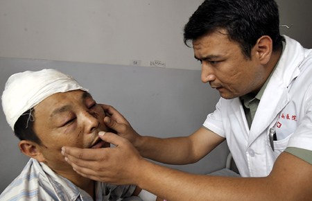 A doctor of Uygur ethnic group examines an injured man at the No. 23 Hospital of the Chinese People's Liberation Army (PLA) in Urumqi, capital of China's Xinjiang Uygur Autonomous Region, in this picture taken on July 7, 2009. Xinjiang is slowly returning to normal after a deadly riot broke out in capital city Urumqi on July 5, 2009. 