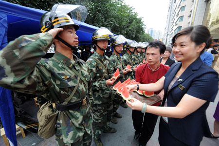 A policeman salutes when an employee of Rongdu Hotel sends watermelons to him in Urumqi, capital of northwest China's Xinjiang Uygur Autonomous Region, on July 13, 2009. All walks of life in Urumqi have kept sending fruits, food and water to policemen who are ensuring the security here in recent days. 