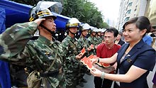 A policeman salutes when an employee of Rongdu Hotel sends watermelons to him in Urumqi, capital of northwest China's Xinjiang Uygur Autonomous Region, on July 13, 2009. All walks of life in Urumqi have kept sending fruits, food and water to policemen who are ensuring the security here in recent days.