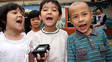 Three kids sing Uygur children's songs and request the reporter record their singing in a kindergarten in Hetian, a city in northwest China's Xinjiang Uygur Autonomous Region on Monday, July 13, 2009.