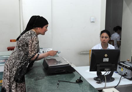 A client conducts procedures at the Santunbei Branch of the Urumqi Post Bureau in Urumqi, capital of northwest China&apos;s Xinjiang Uygur Autonomous Region, on July 14, 2009. 