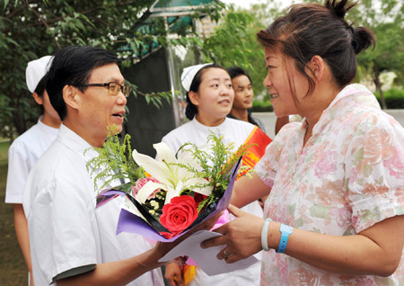 Yao Lumei (R), who was wounded in the July 5 riot, presents flowers to doctor Zhang Dekuan for his careful attendance before she leaves the hospital in Urumqi, capital of northwest China's Xinjiang Uygur Autonomous Region, on July 15, 2009. 