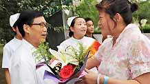 Yao Lumei (R), who was wounded in the July 5 riot, presents flowers to doctor Zhang Dekuan for his careful attendance before she leaves the hospital in Urumqi, capital of northwest China's Xinjiang Uygur Autonomous Region, on July 15, 2009.