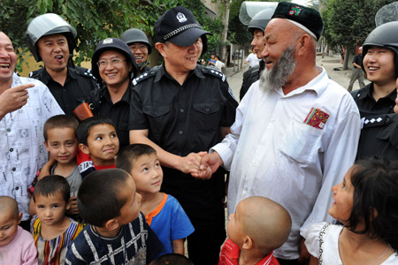 Xu Tao (C), a member of the special police force, shakes hands with an elder Uygur man, on Pingding Hill in Urumqi, capital of northwest China's Xinjiang Uygur Autonomous Region, July 14, 2009. The residents of various ethnic groups living on Pingding hill resumed their peaceful and harmonious life after the deadly July 5 riot, thanks to the peacekeeping police force who managed to maintain ethnic unity and social stability here by helping locals recognize the truth and publicising the ethnic policy with their sincerity.