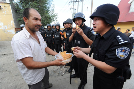 Mohammad presents his home-made food to members of the special police force on Pingding Hill in Urumqi, capital of northwest China's Xinjiang Uygur Autonomous Region, July 14, 2009. The residents of various ethnic groups living on Pingding hill resumed their peaceful and harmonious life after the deadly July 5 riot, thanks to the peacekeeping police force who managed to maintain ethnic unity and social stability here by helping locals recognize the truth and publicising the ethnic policy with their sincerity.