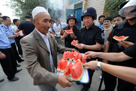 Ma Hongjiang presents watermelon to members of the special police force on Pingding Hill in Urumqi, capital of northwest China's Xinjiang Uygur Autonomous Region, July 14, 2009. The residents of various ethnic groups living on Pingding hill resumed their peaceful and harmonious life after the deadly July 5 riot, thanks to the peacekeeping police force who managed to maintain ethnic unity and social stability here by helping locals recognize the truth and publicising the ethnic policy with their sincerity. 