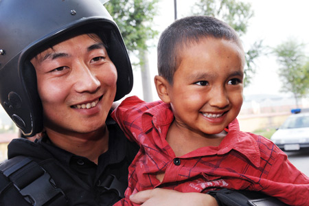 He Wei (L), a member of the special police force, poses with Uygur boy Enwa on Pingding Hill in Urumqi, capital of northwest China's Xinjiang Uygur Autonomous Region, on July 14, 2009.