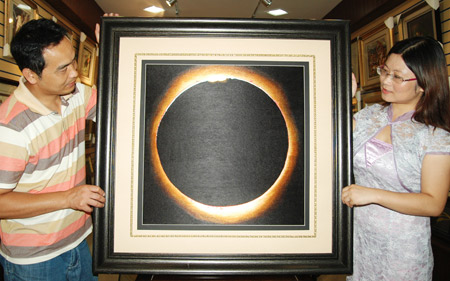 Chen Yinghua (R) shows her embroidery 'Total Solar Eclipse' in Suzhou City of east China's Jiangsu Province, on July 7, 2009. Recently finished by embroidery master Chen Yinghua after a total of 120 days' work, the embroidery 'Total Solar Eclipse' will be displayed on an academic meeting on solar coronal dynamics hosted by the International Astronomical Union in Suzhou.