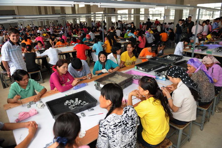 Workers from Han and Uygur ethnic groups sit together while working at production lines at the Xuri Toy Factory in Shaoguan, south China's Guangdong Province, where a brawl between hundreds of people from Han and Uygur ethnic groups led to two deaths early June 26.